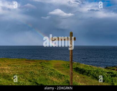 A rainbow forms on the horizon off the coast of Orkney.