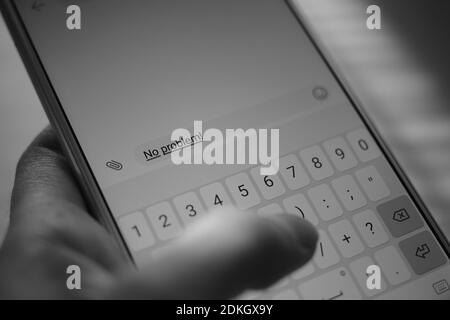Human hand typing on a smartphone screen a message No problem. BW photo Stock Photo