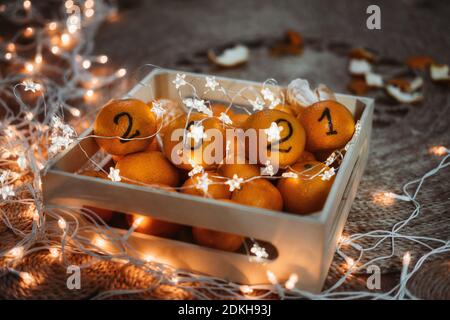 Christmas greeting card with oranges, tangerines with numbers 2021 and garland lights. New Year 2021 is Coming, Cozy Christmas Concept. Black Numbers Stock Photo