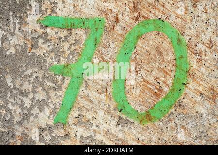 Green painted number 70 on a textured concrete background Stock Photo