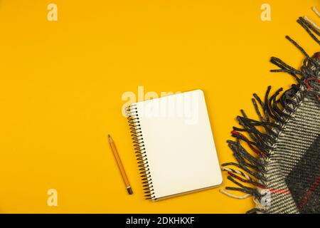 Simple workplace with notepad, pencil and plaid on yellow background with place for text, copy space photo Stock Photo