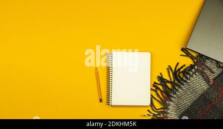 Simple cozy workplace with notepad and laptop, pencil and blanket on yellow background with place for text, copy spacephoto Stock Photo