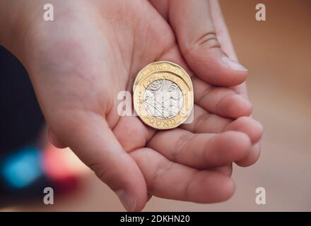 Kid hand showing money two pound coins on his hands,Child holding new British one pound on both hands, New pound coin, 2017 design