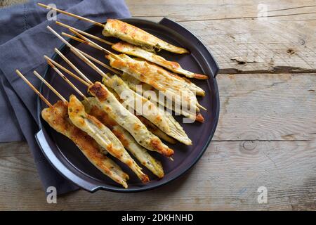 Fried mediterranean chicken skewers served as finger food snack for a festive party, rustic wooden table with copy space, high angle view from above