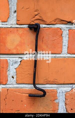 old rusty metal hook on red brickwork wall background Stock Photo