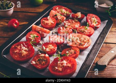 Preparation of Tomato Preserves in Olive Oil with Thyme and Garlic on Baking Dish Stock Photo