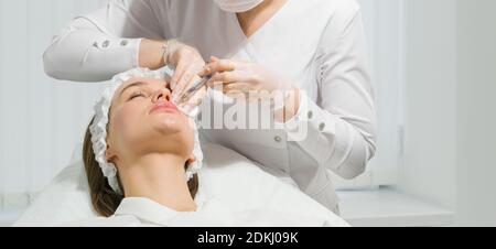 lip shape correction procedure in a cosmetology salon. The specialist makes an injection on the lips of the patient. Lip augmentation Stock Photo