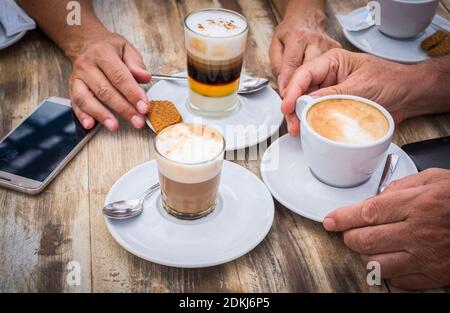 Close up of senior old hands from mature couple enjoy the breakfast at the bear with coffee and cappuccino Stock Photo
