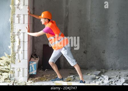profession, construction and building - happy smiling worker or builder in helmet over room with working equipment at new home or apartment background Stock Photo