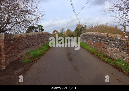 Quiet country lane on a hump back bridge over the Taunton and Bridgewater canal in Somerset on an overcast autumn day Stock Photo