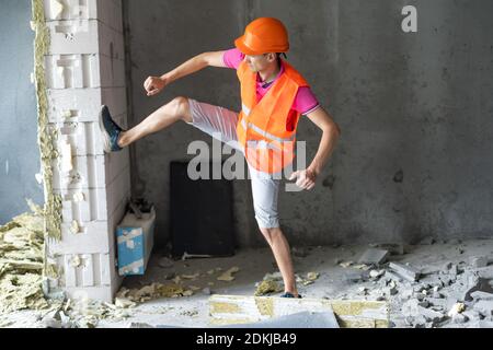 profession, construction and building - happy smiling worker or builder in helmet over room with working equipment at new home or apartment background Stock Photo