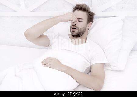 Snoring can increase risk headaches. Common symptom of sleep apnea. Causes of early morning headache. Migraine headaches. Sleep problems can lead to headaches in morning. Handsome man relaxing in bed. Stock Photo