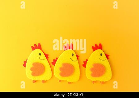 Three cute yellow felt chickens in a row, handmade, diy, kids Easter crafts, copy space, funny handmade idea. Stock Photo