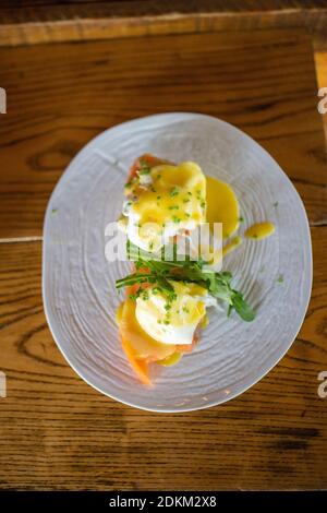 Tasty eggs benedict on a vintage-looking wooden table Stock Photo