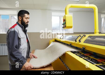 Man operating carpet automatic washing machine in professional laundry service Stock Photo