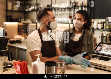 Coffee shop owners with face masks, lockdown, quarantine, coronavirus, back to normal concept Stock Photo