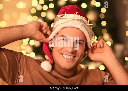 Handsome man in Santa hat against defocused lights Stock Photo