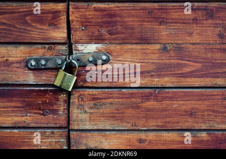 Closed padlock on a painted brown pine wooden door Stock Photo