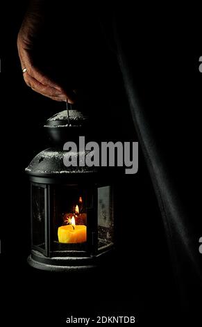 Hand holding a rustic candle holder on dark background. Stock Photo