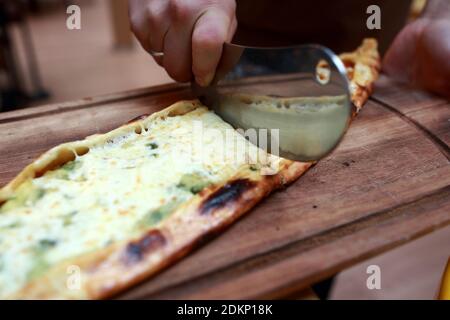 Chef cutting Sebzeli Pide on a wooden plate