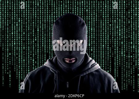 Masked cyber terrorist with black balaclava and hoodie in the dark Stock Photo