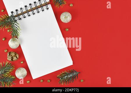 White empty notebook surrounded by Christmas decoration in corner of red background with empty copy space Stock Photo