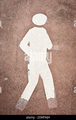 an old, weathered and fading pedestrian symbol with parts of the symbol being broken away, vertical Stock Photo