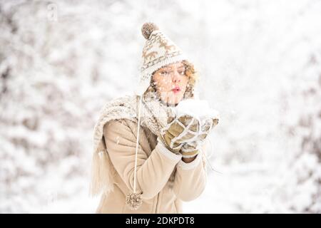 happy woman blow snow from hands. girl in trendy winter coat. girl wear warm mittens and hat. good mood any weather. winter and people concept. having fun. being in playful mood. blow snowflakes away. Stock Photo