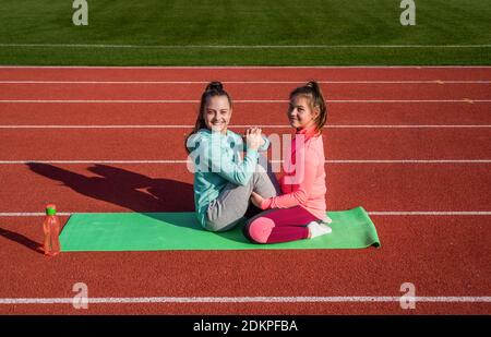 Training to be the best. children do exercise on track. healthy childhood. workout on fresh air. thirsty and hydration. teen girls arm wrestling on stadium. kids in sportswear relax on yoga mat. Stock Photo