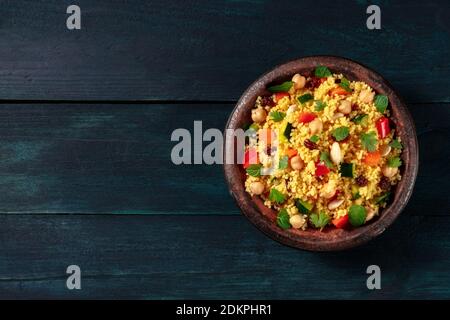 Couscous with vegetables in a tajine, shot from the top on a dark blue wooden background with copy space Stock Photo