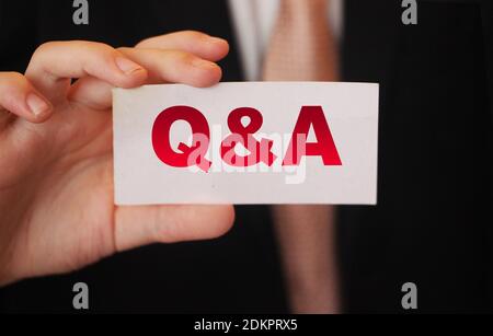 Q and A Questions and Answers sign on business card shown by a businessman,. Business concept. Stock Photo