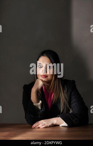 PORTRAIT OF A WOMAN SITTING AND POSING IN FRONT OF CAMERA