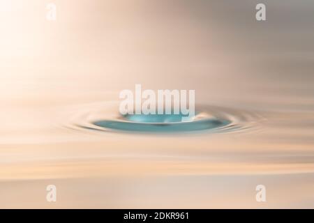 Close up photo of a water droplet hitting the surface of water and creating a cavity. This photo can be used for all kinds of purposes. Stock Photo