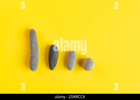 Flat lay in a trendy 2021 new colors. Illuminating Yellow and Ultimate Gray. Color of the Year 2021. Grey sea stones on yellow background Stock Photo
