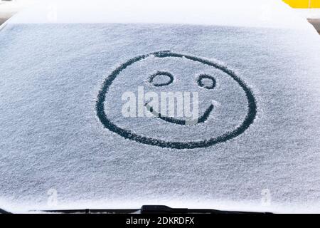 image of a smiling face in the snow on the windshield of a car on a frosty winter day Stock Photo