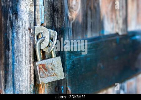 Old metal lock on the door of a wooden house. Close up. Copy space. Selective focus. Stock Photo
