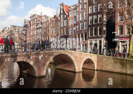 Amsterdam, Netherlands - February 24, 2017: Street view of Amsterdam old town at sunny day with walking people Stock Photo