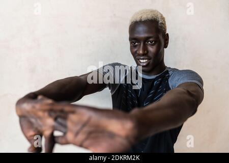 Young athletic happy african american man smiling while doing workout indoors Stock Photo
