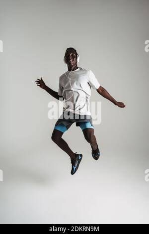 Happy african american guy listening music with headphones and jumping isolated over white background Stock Photo