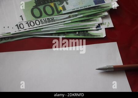 100 euro bills, pink leather wallet, pen and blank paper with copyspace. Business profit financial concept. Stock Photo