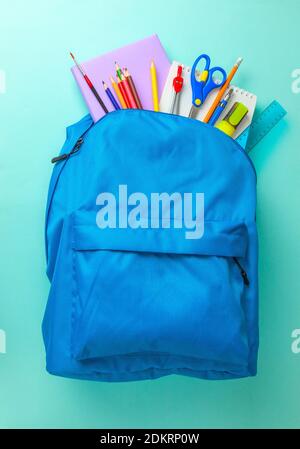 School bag. Backpack with supplies for school on blue background. Copy space for text. Stock Photo