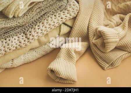 Warm woolen clothing for the winter season lies folded in a pile. The comfort of home. Fashionable knitted sweaters. Stock Photo