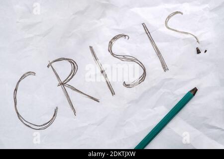 Unfinished text crisis, broken pencil on crumpled white paper sheet  Stock Photo