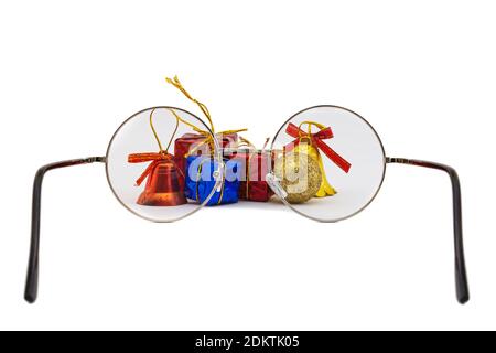 Christmas gift packages and ornaments with red, blue and yellow colors behind round eyeglasses isolated on white background. Stock Photo