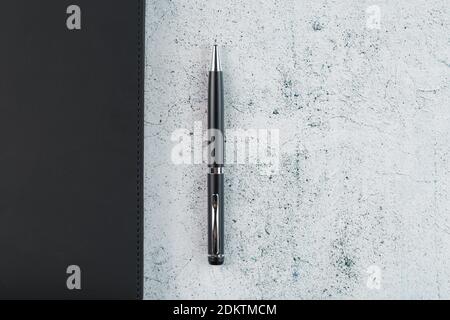 Black Notepad with a black pen on a gray background. Top view, minimalistic concept. Free space. Stock Photo