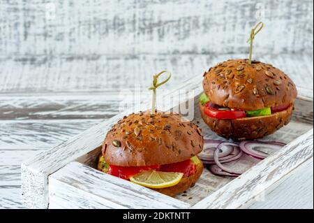 whole-grain bun stuffed with salad, salmon, avocado and tomatoes. Healthy food concept. Stock Photo