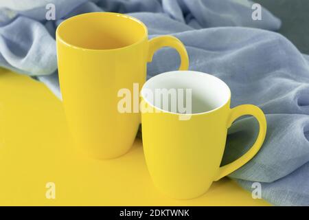 Two yellow cups on grey and yellow background. Colors of the year 2021. Stock Photo