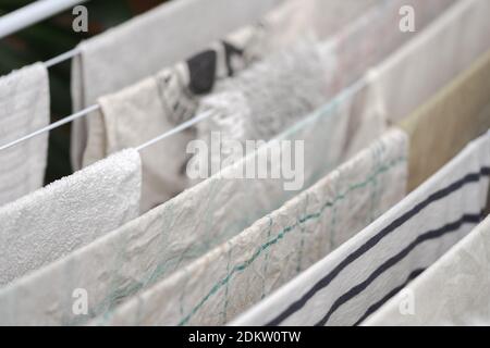 Detail of dish towels and other white laundry hanging on clothes horse to dry Stock Photo