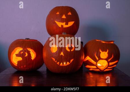 Four lit Jack O Lantern carved pumpkins glowing on Halloween night Stock Photo