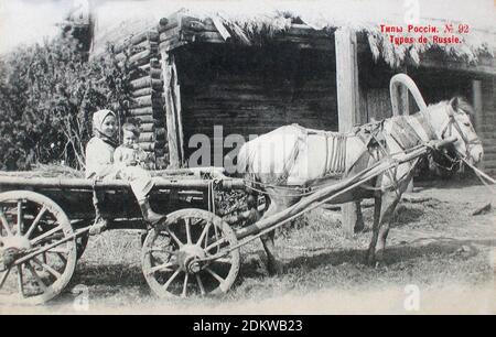 Retro postcard of Types and Costumes of Russia. A young peasant woman with a child in a cart. Russian Empire. 1904 Stock Photo